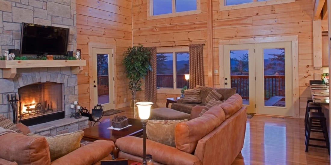 Log home great room with fireplace and lots of windows and extended ceilings
