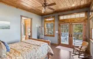 Wood ceiling in bedroom with double doors and transom leading to porch
