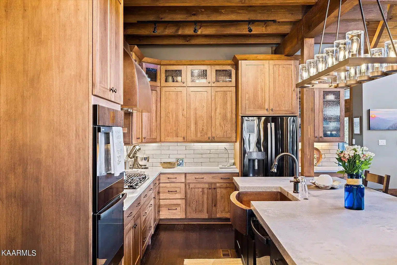 Rustic Kitchen with double oven, gas range and transom windows over upper cabinets and tile backsplash. The curved front copper sink makes a nice addition
