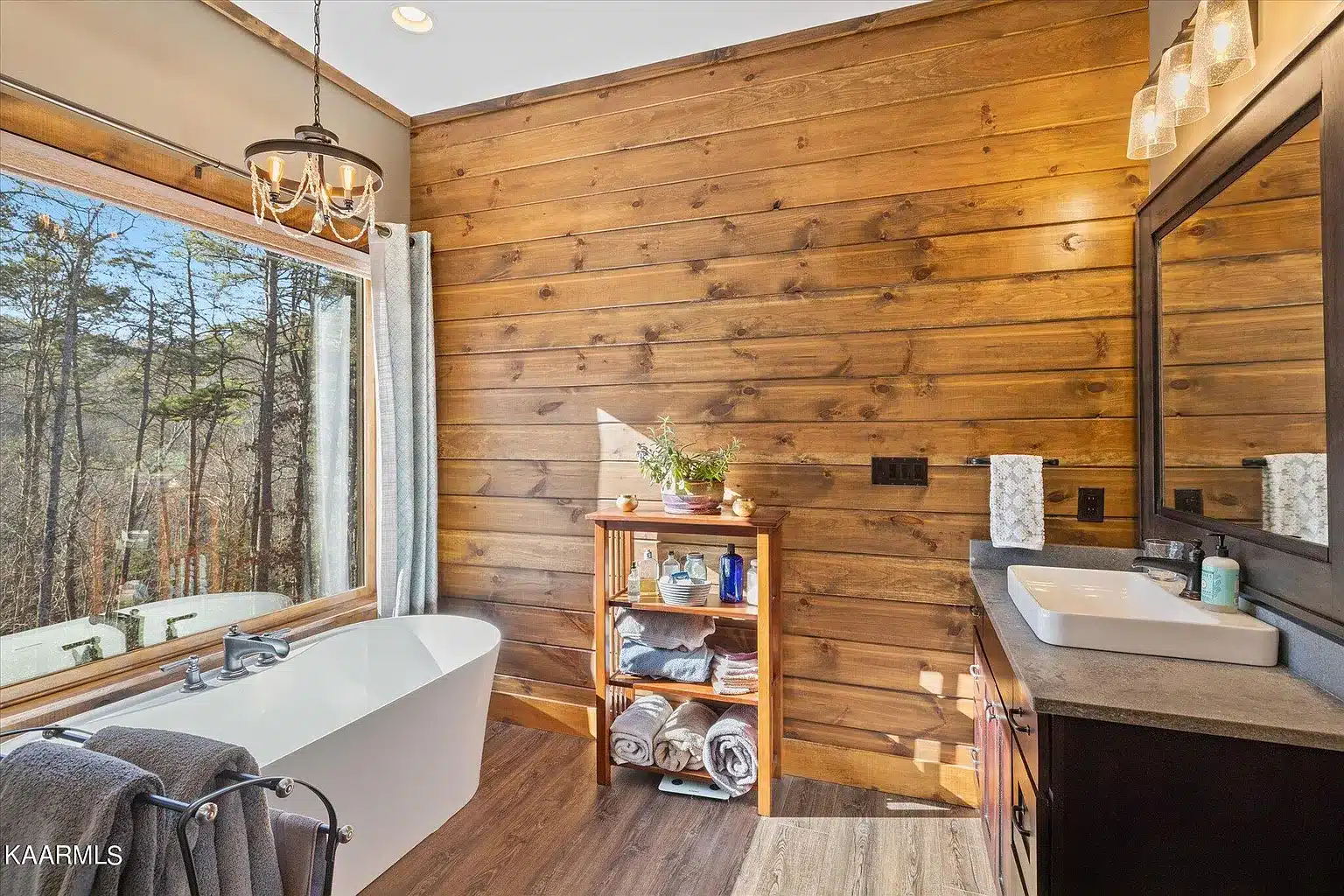 Large Picture framed window at soaker tub with rustic interior siding and chandelier