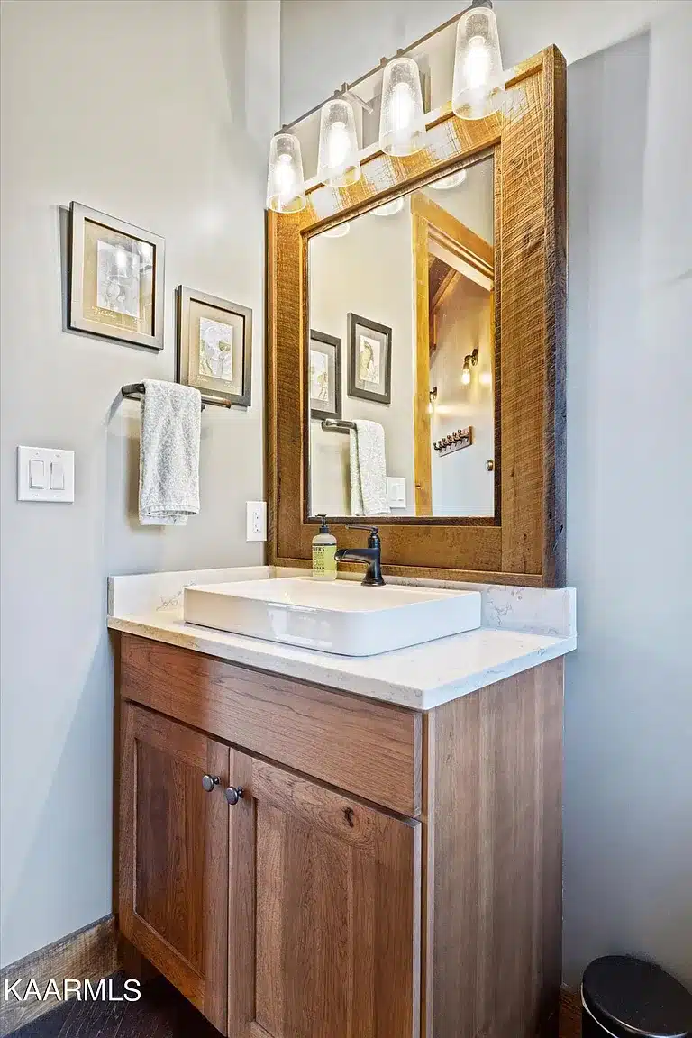 Custom vessel sink with rough sawn trim around mirror and lighting above