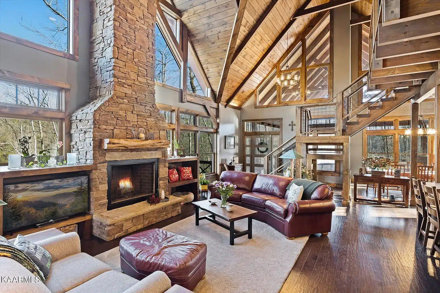 Great room with large fireplace and built ins with exposed timber and custom trapezoid glass and custom leather furniture