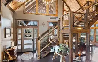 Timber home heavy timber stairs in great room with entry door and custom glass above