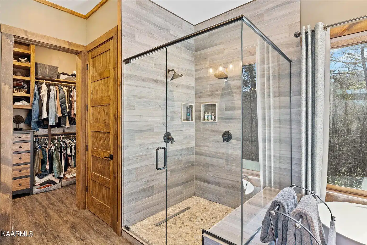 All glass shower with seat, wooden wall tile textures and stone floor tile used with long floor drain for more water flow