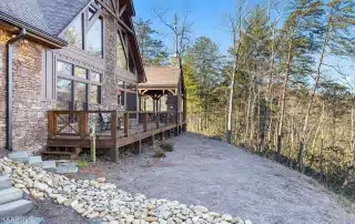 Stone and timber home with board and batten siding and large windows and timber truss for maximum views from the inside